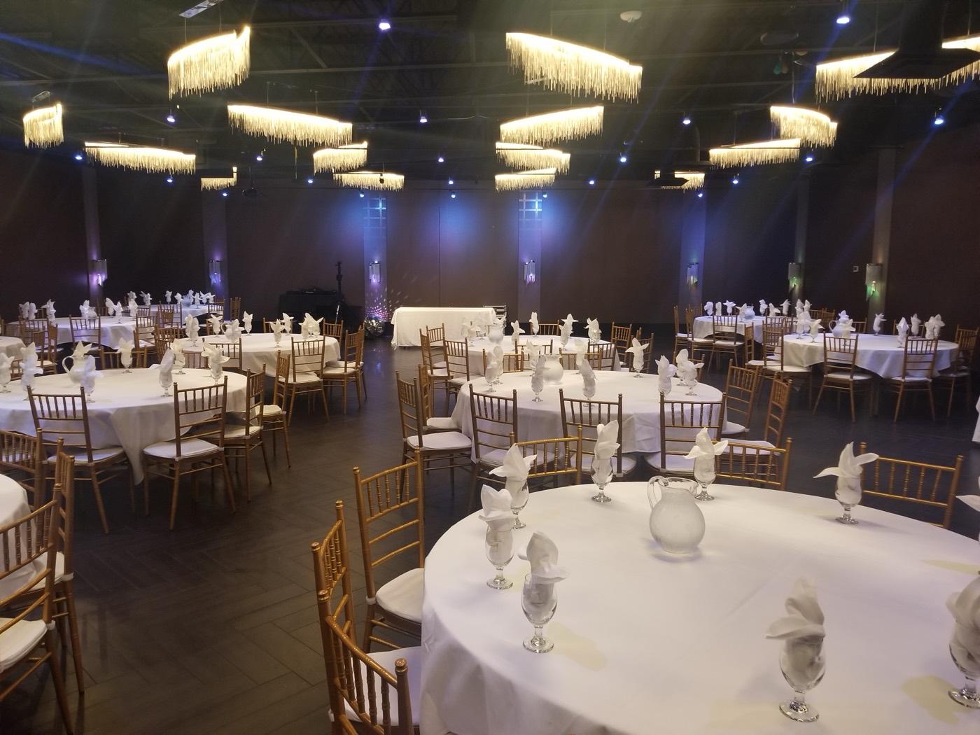 All-white round banquet tables with gold Chiavari chairs at India 101 banquet hall in Irving, TX