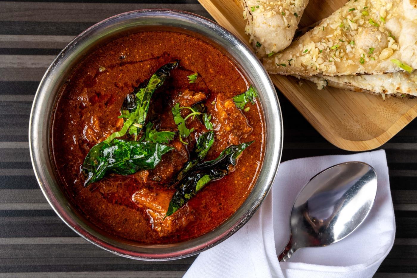 Spicy Andhra Halal chicken curry with fried curry leaves at India 101 in Irving, TX