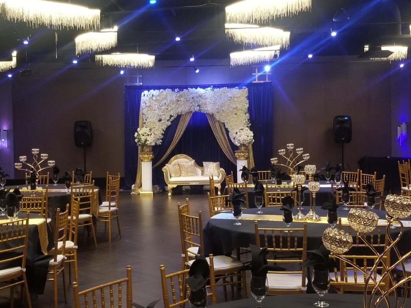 India 101 banquet hall decorated with a floral stage and gold chairs for a wedding reception