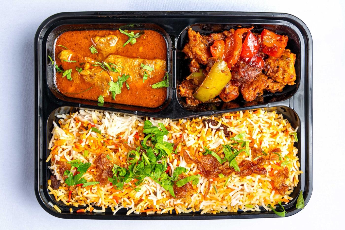 Takeout tray with biryani, curry and Indo-Chinese chili chicken