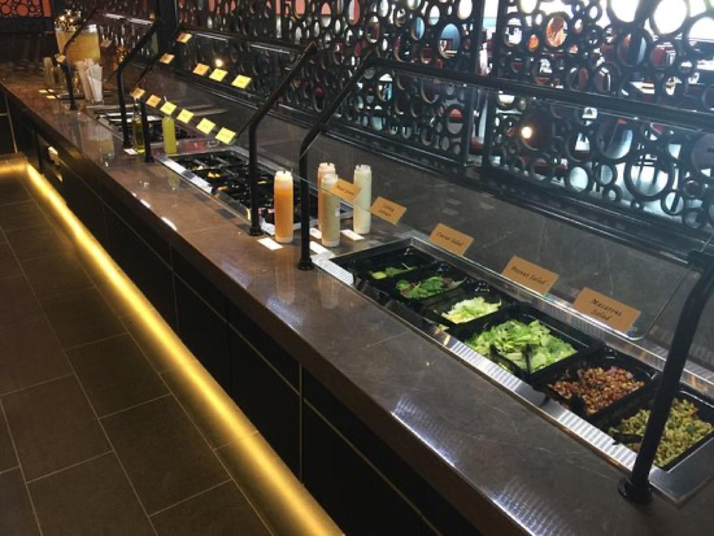 Salad bar with fresh greens, dressings, and cold sides at India 101 in Irving, TX