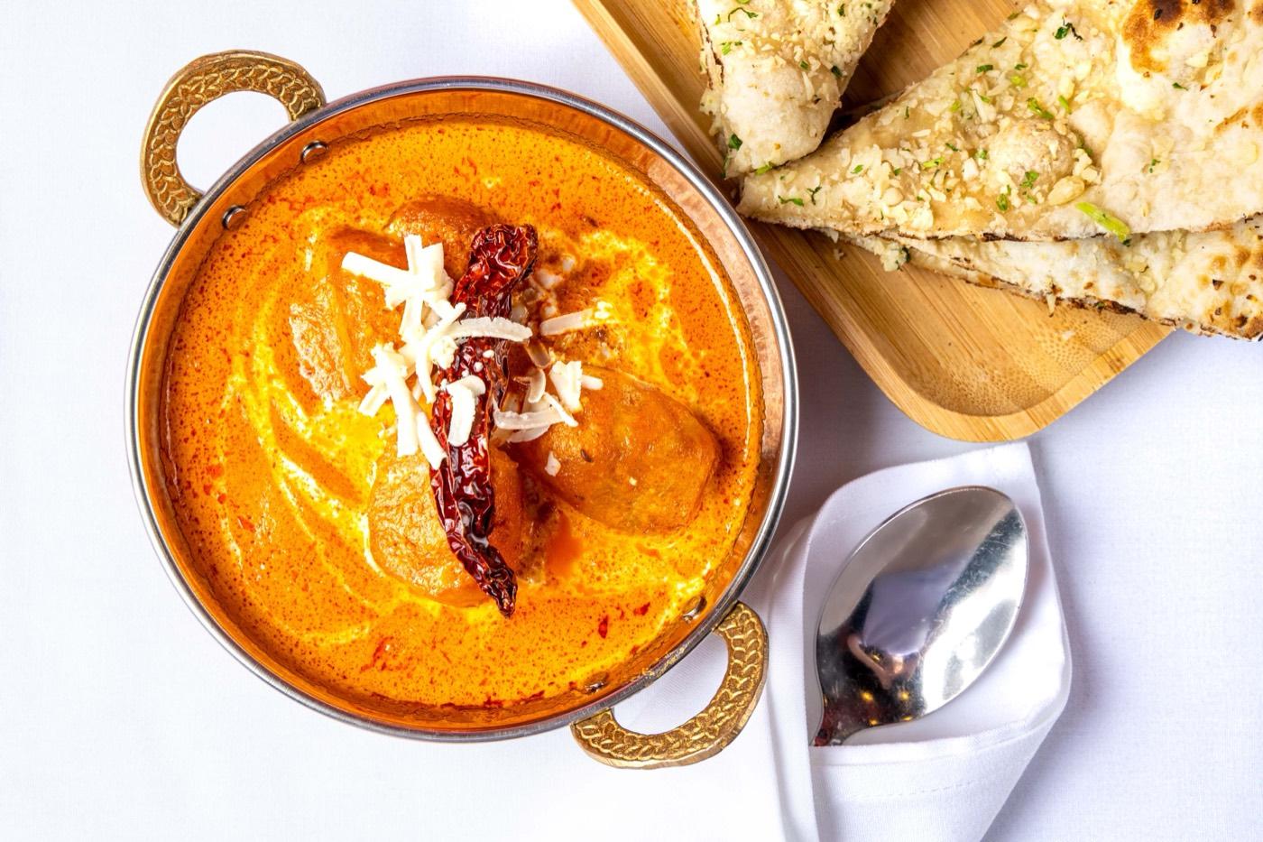 Creamy Halal butter chicken in a copper karahi with garlic naan at India 101 in Irving, TX
