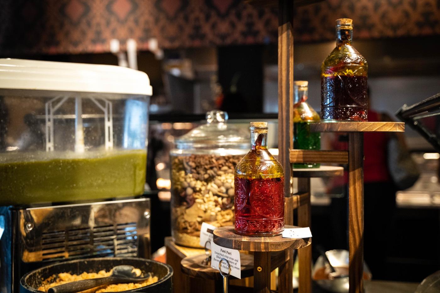Chaat station with green spiced water dispenser and infused water bottles at India 101 in Irving, TX