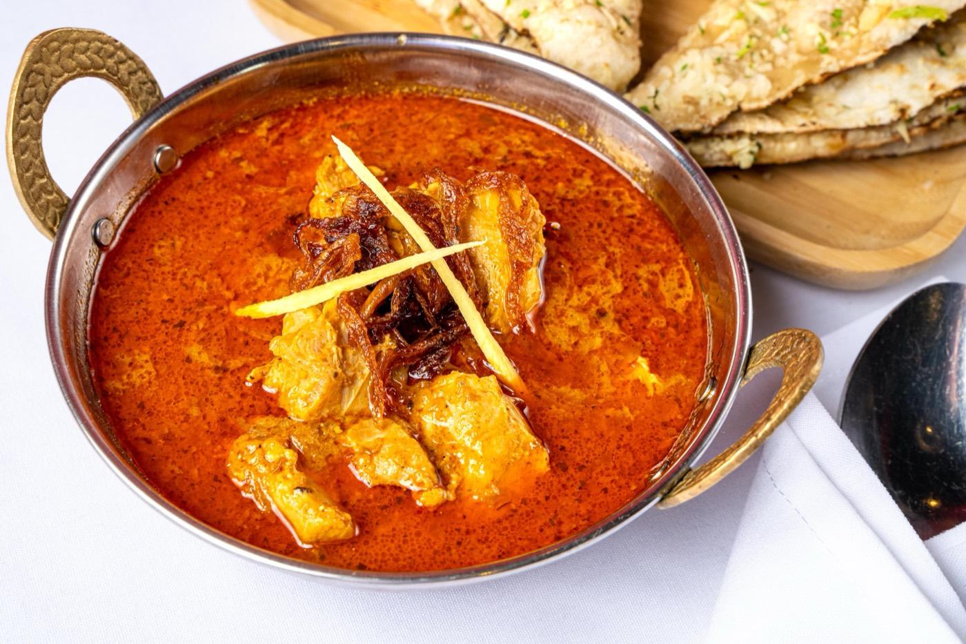 Close-up of Halal chicken masala in fiery red gravy with fried onions at India 101 in Irving, TX