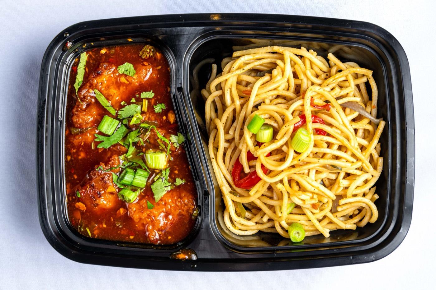 Takeout box of Indo-Chinese chili chicken and Hakka noodles from India 101
