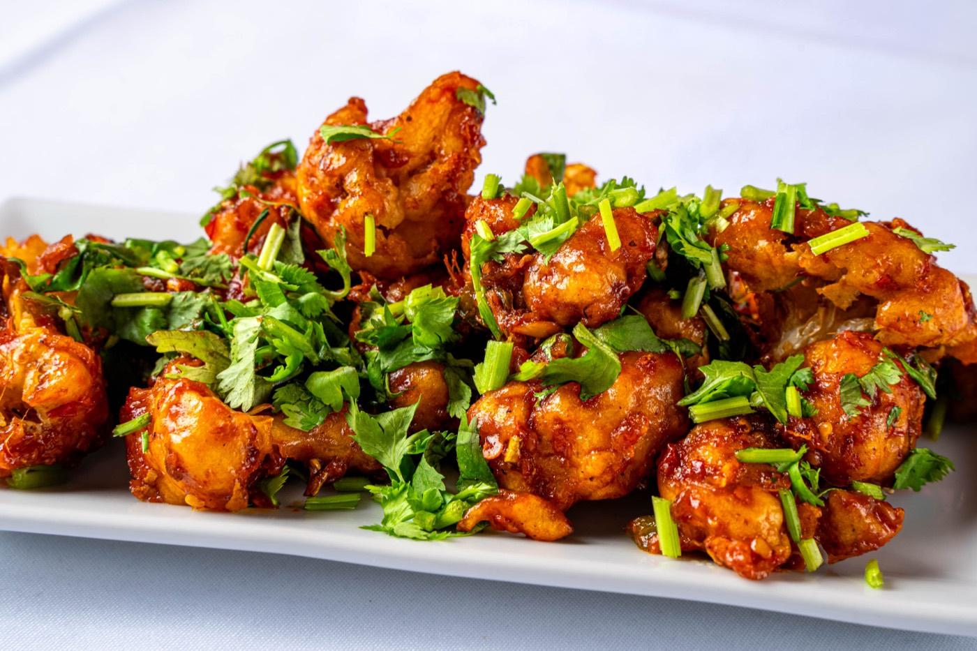 Close-up of battered Indo-Chinese chilli chicken with herbs at India 101 in Irving, TX