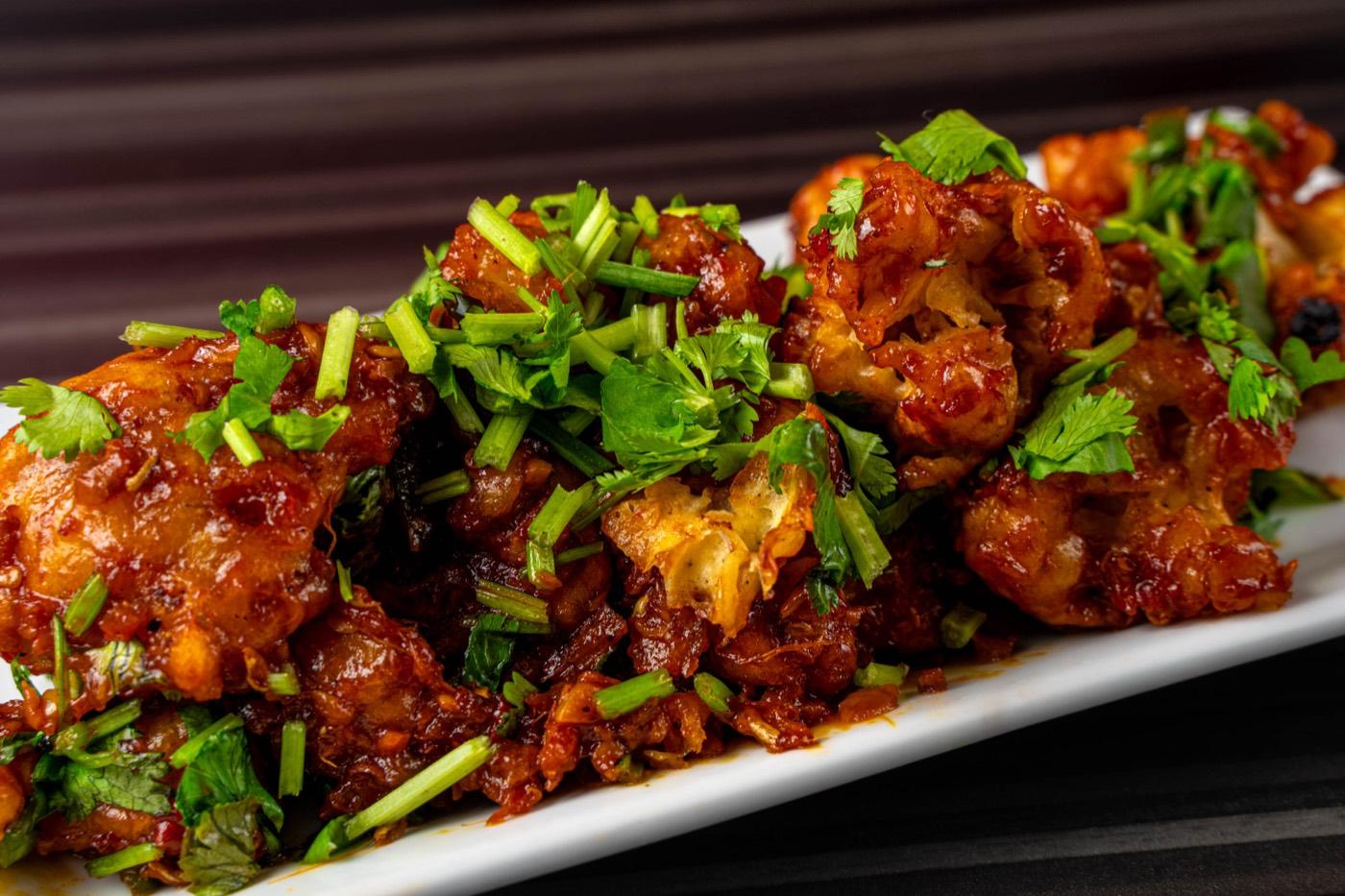 Close-up of glossy Indo-Chinese chilli chicken with scallions at India 101 in Irving, TX