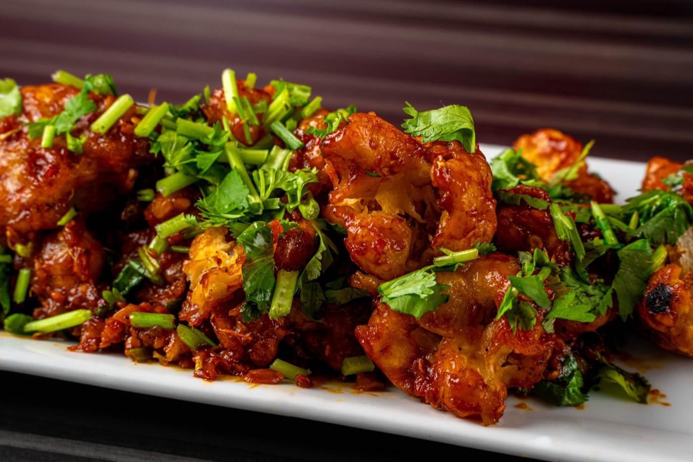 Indo-Chinese chilli chicken garnished with cilantro and scallions at India 101 in Irving, TX