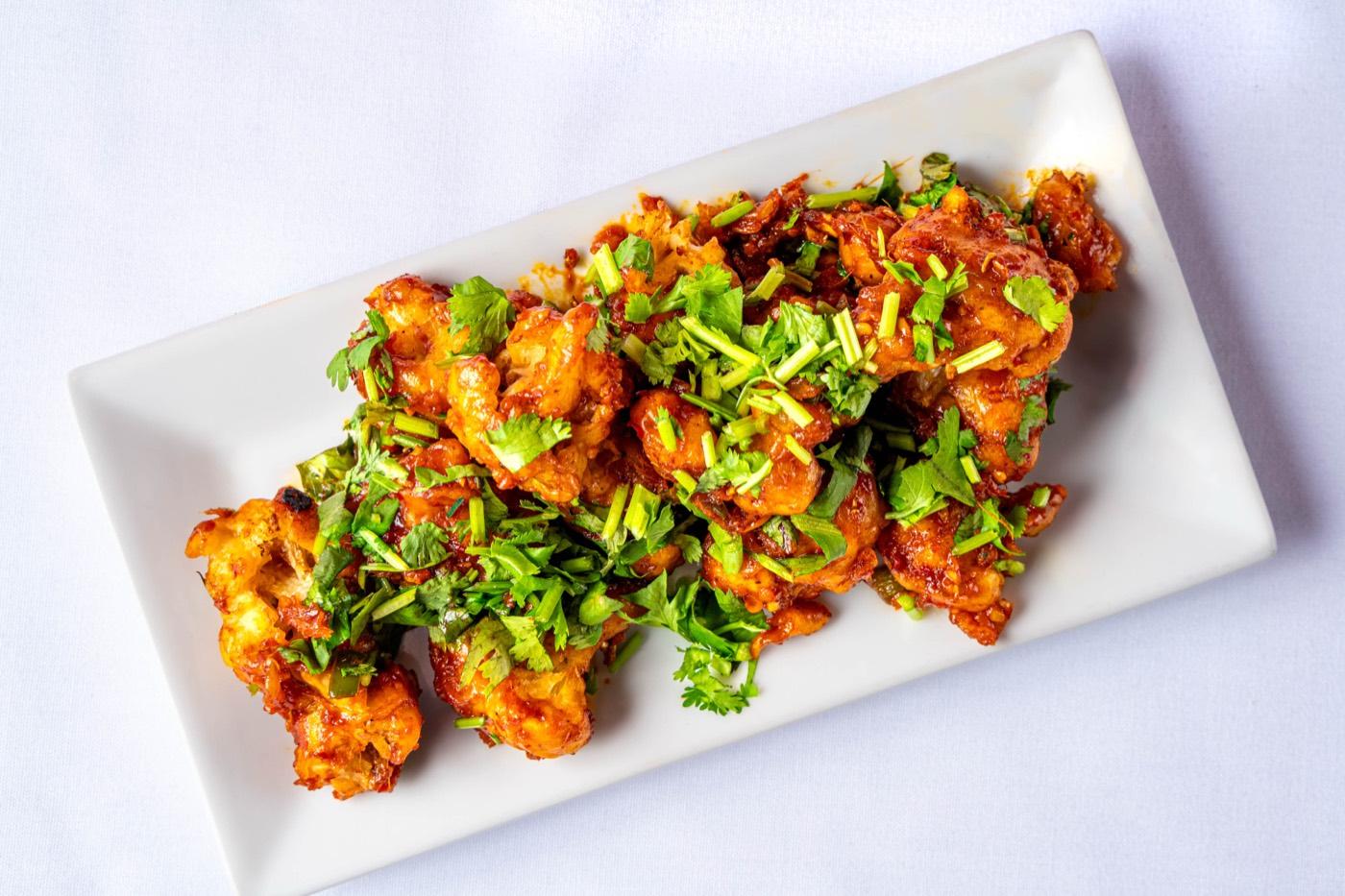 Overhead Indo-Chinese chilli chicken on a white platter at India 101 in Irving, TX