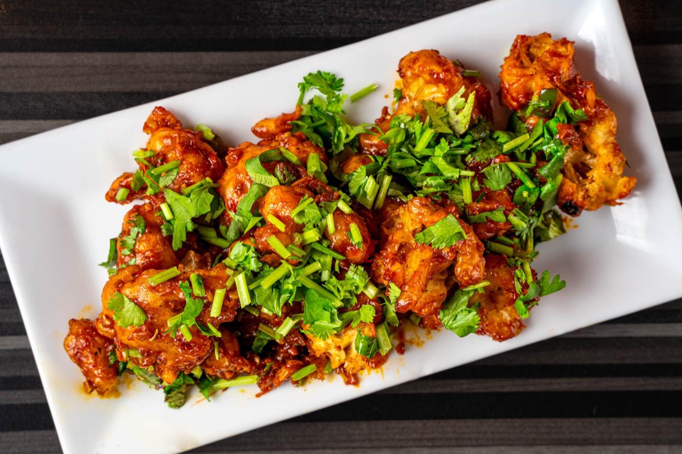 Overhead view of Indo-Chinese chilli chicken topped with herbs at India 101 in Irving, TX