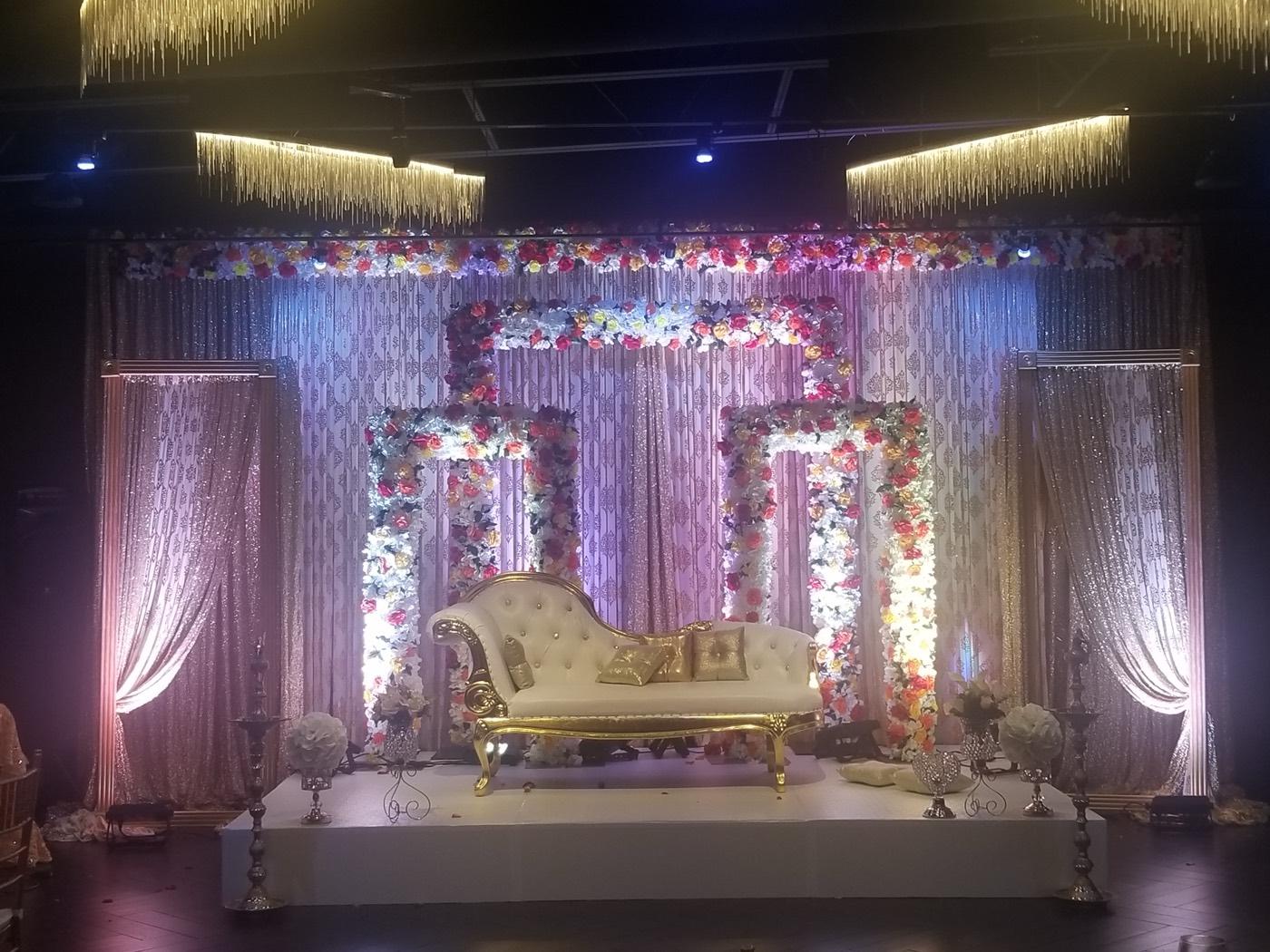 Grand floral arch wedding stage with gold chaise lounge at India 101 banquet hall in Irving, TX