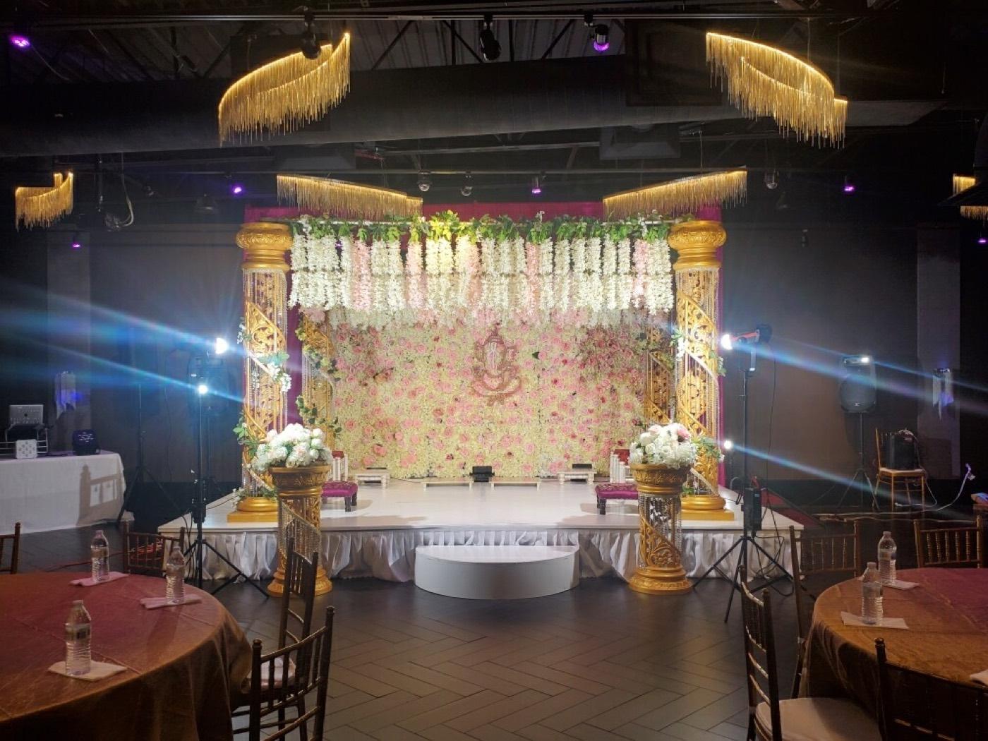 Wedding mandap stage with floral backdrop and gold columns at India 101 banquet hall in Irving, TX