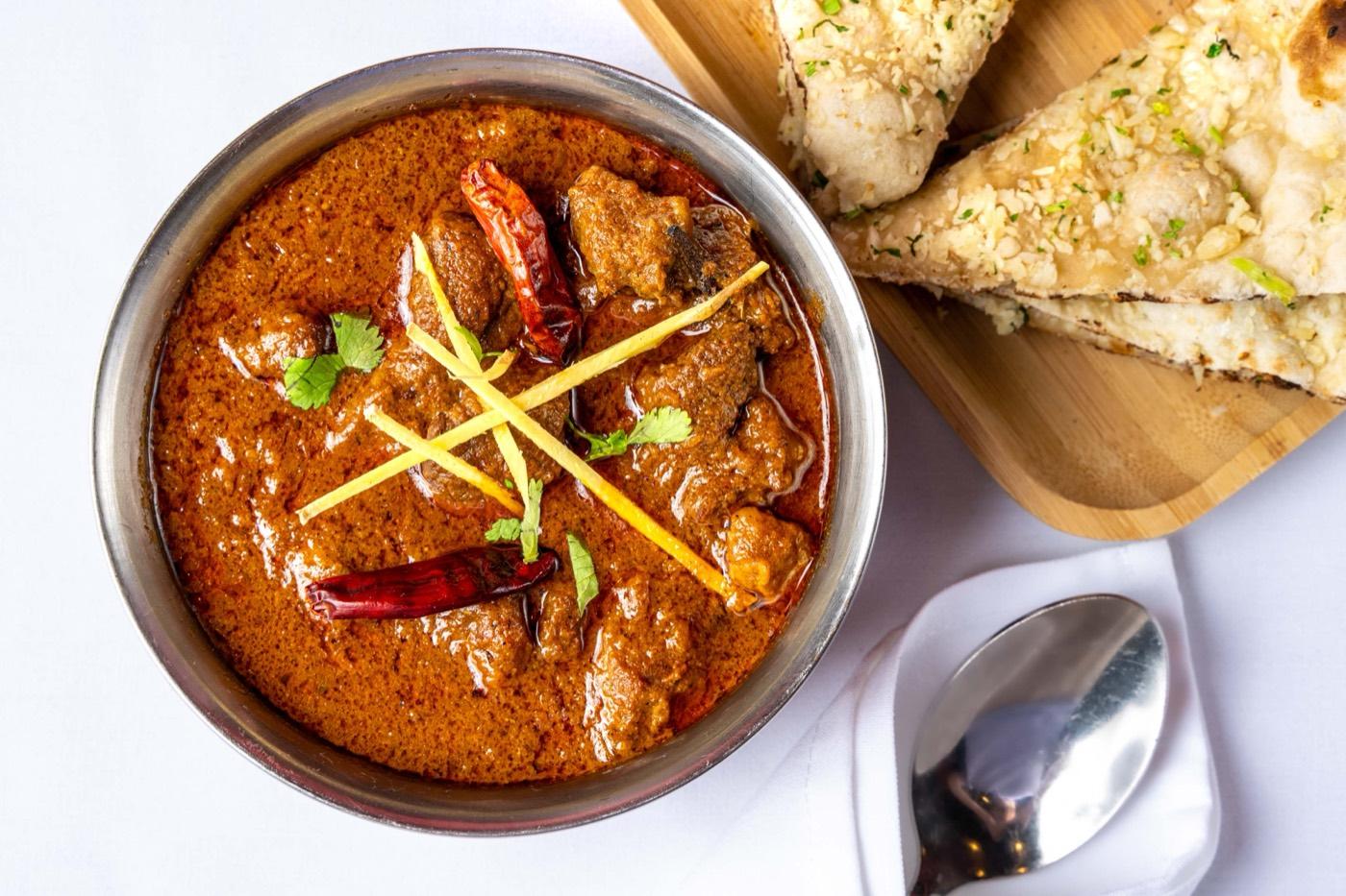 Rich Halal goat curry with ginger julienne and dried chili, served with garlic naan at India 101 in Irving, TX