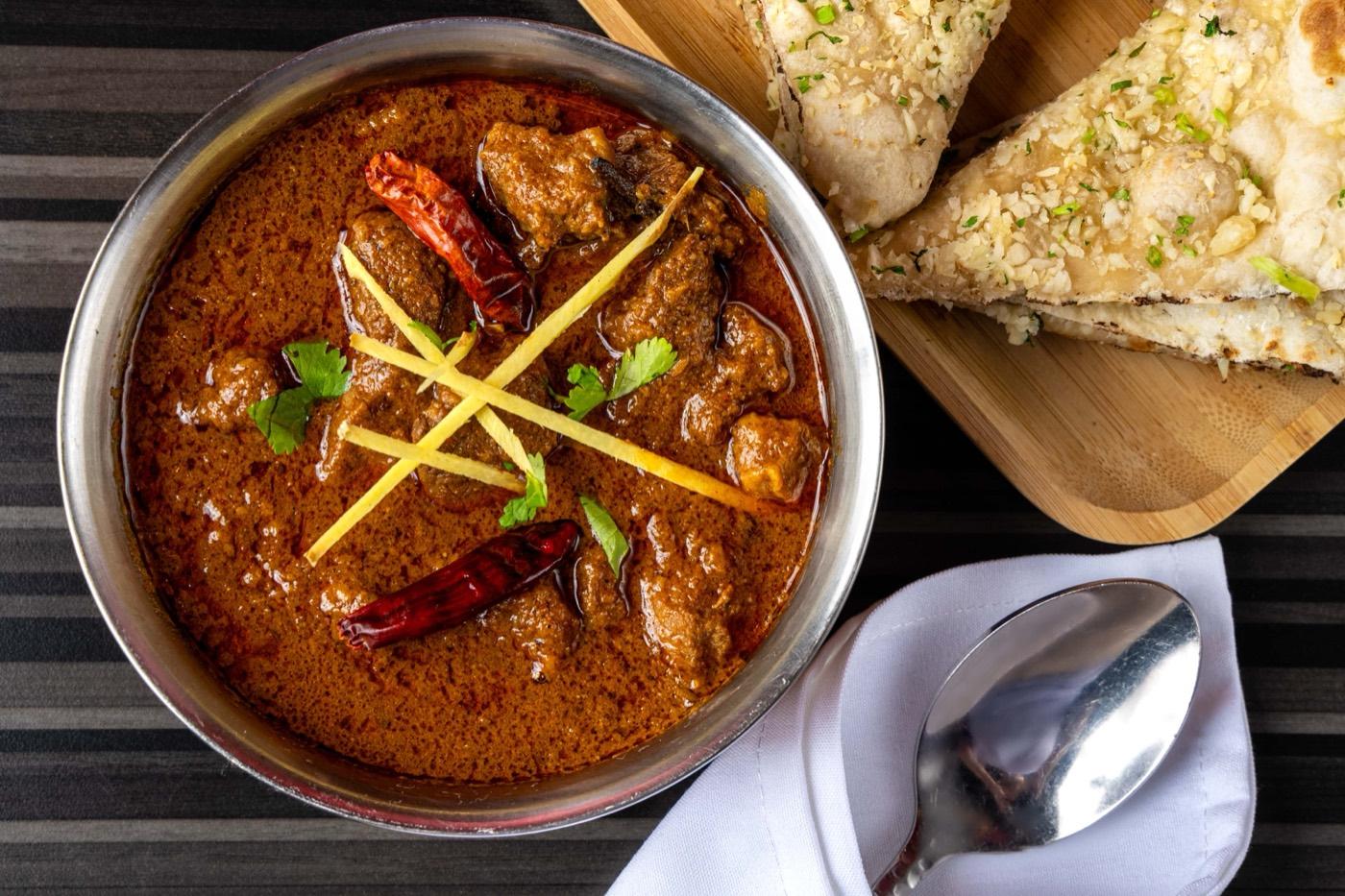 Halal bone-in goat curry with ginger and garlic naan at India 101 in Irving, TX