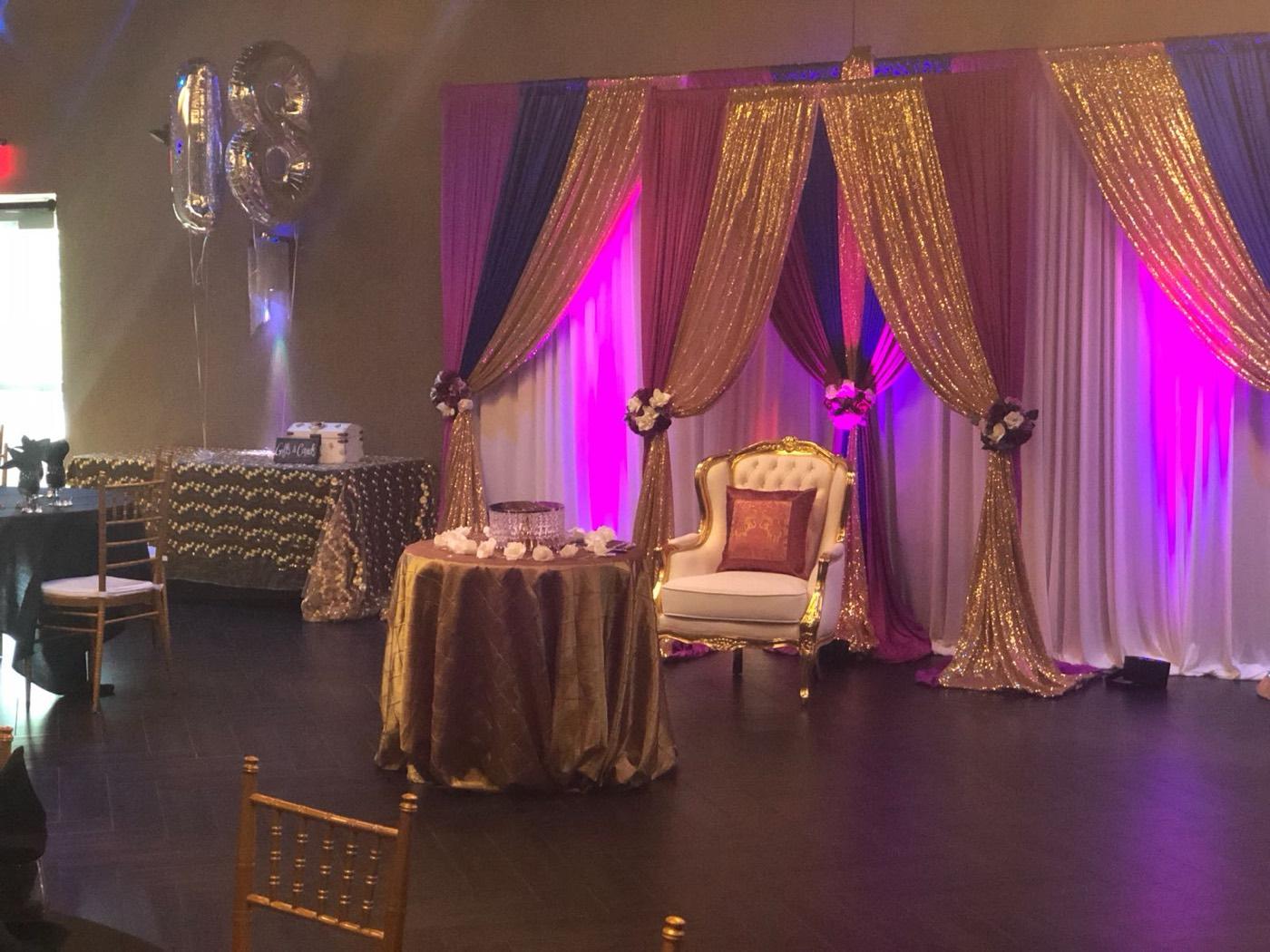Gold sequin draped backdrop with throne chair and cake table at India 101 banquet hall in Irving, TX