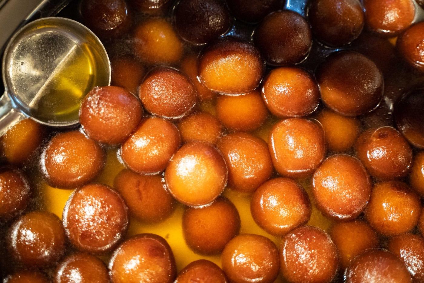 Close-up of golden-brown gulab jamun soaking in sugar syrup at India 101 in Irving, TX