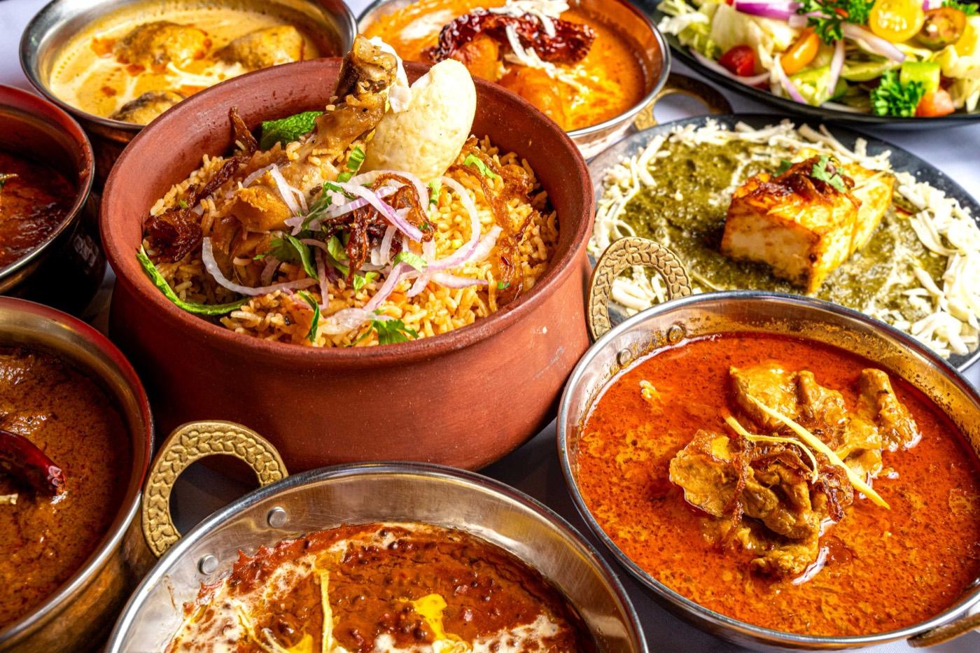 Halal biryani in a clay pot with curries and palak paneer at India 101 in Irving, TX