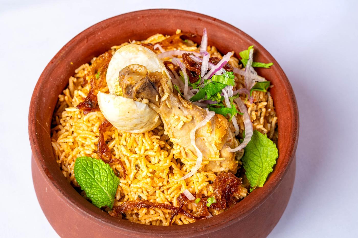 Chicken biryani with drumstick, egg and mint in a clay pot at India 101 in Irving, TX