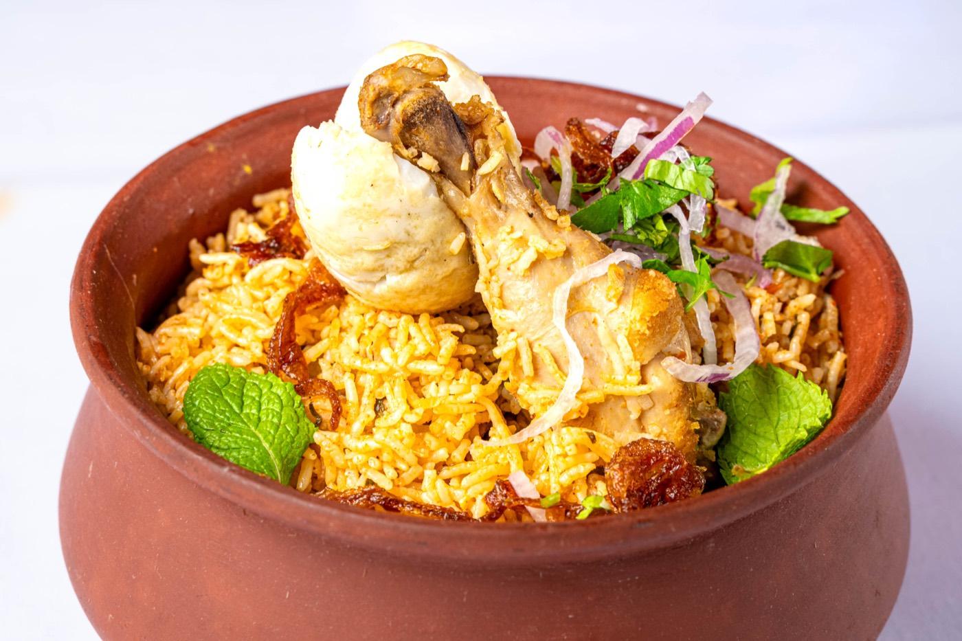 Chicken biryani with drumstick, egg and fried onions in a clay handi at India 101 in Irving, TX