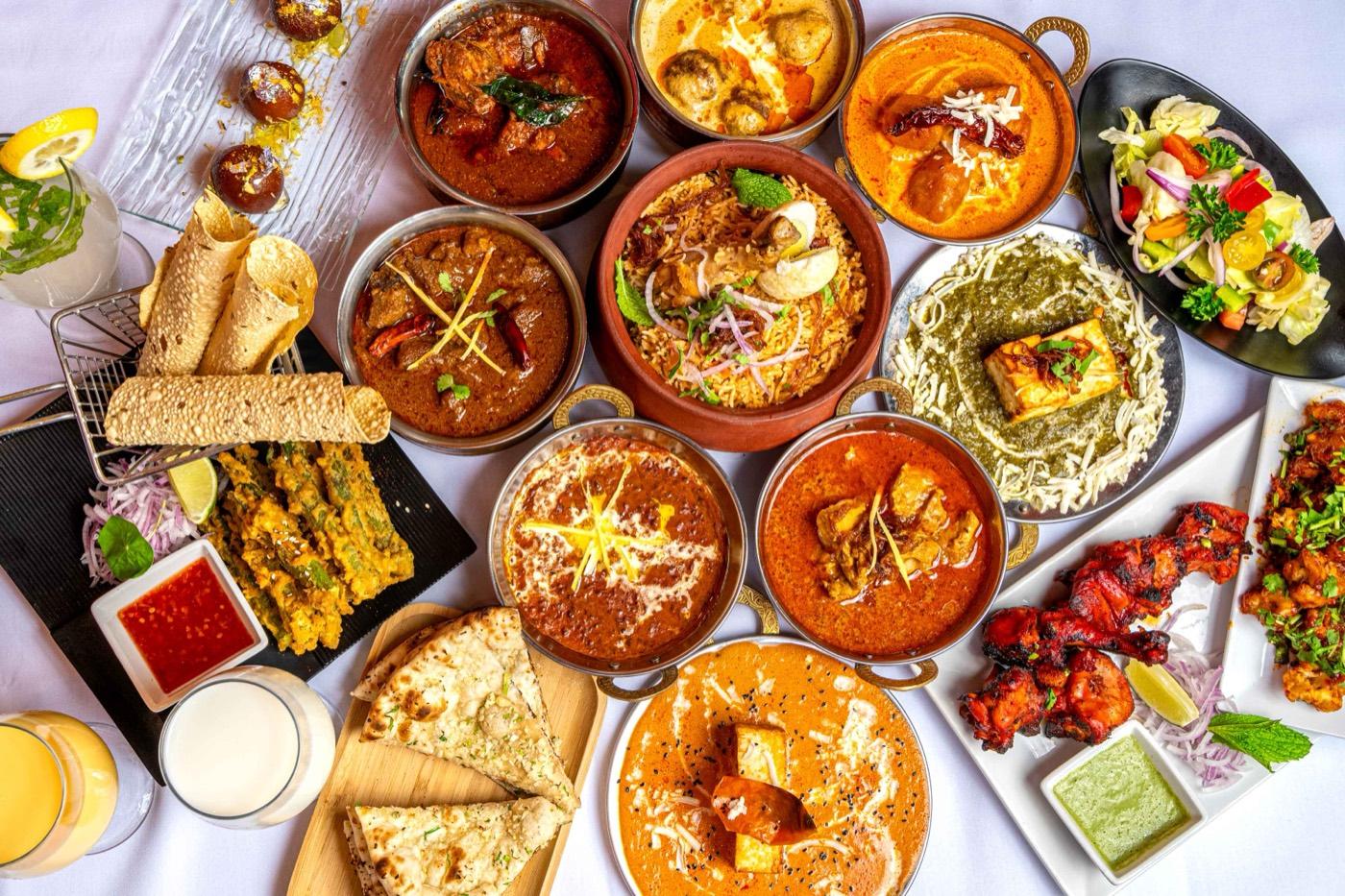 Overhead spread of assorted Halal Indian curries, biryani, tandoori and paneer at India 101 in Irving, TX
