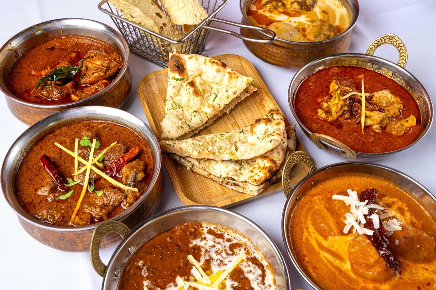 Overhead view of assorted Halal Indian curries with naan and papadum at India 101 in Irving, TX