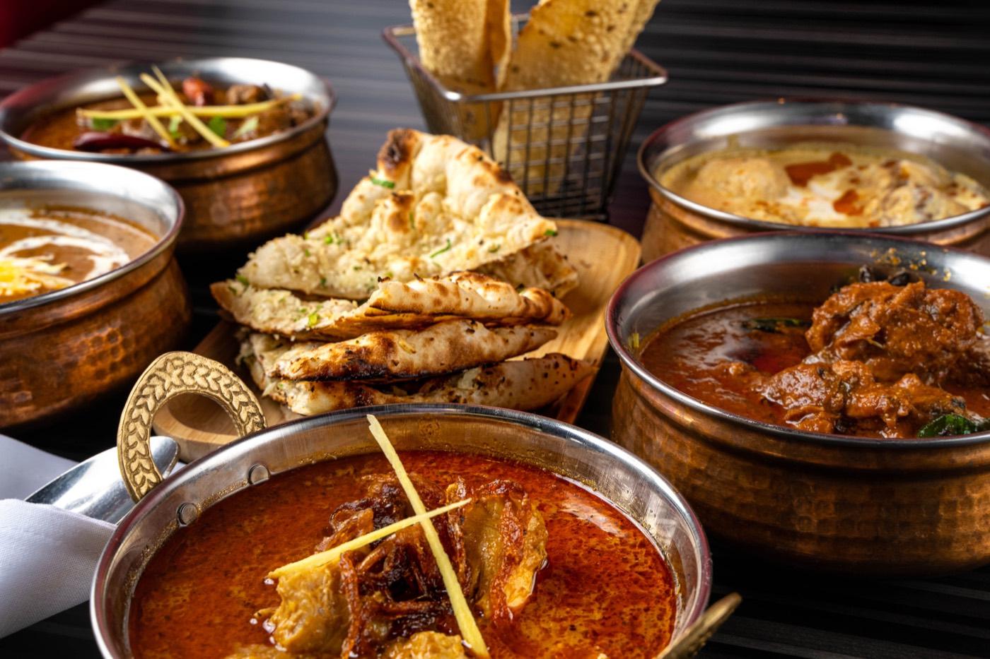 Halal Indian curries in copper bowls with naan and papad at India 101 in Irving, TX