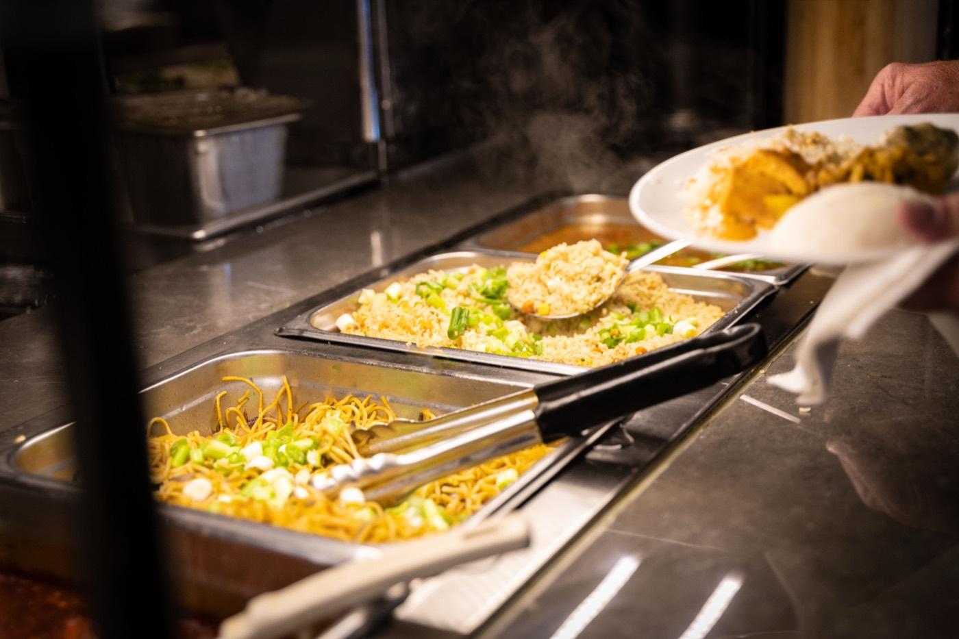 Guest serving fried rice and Hakka noodles from the Indo-Chinese buffet at India 101 in Irving, TX