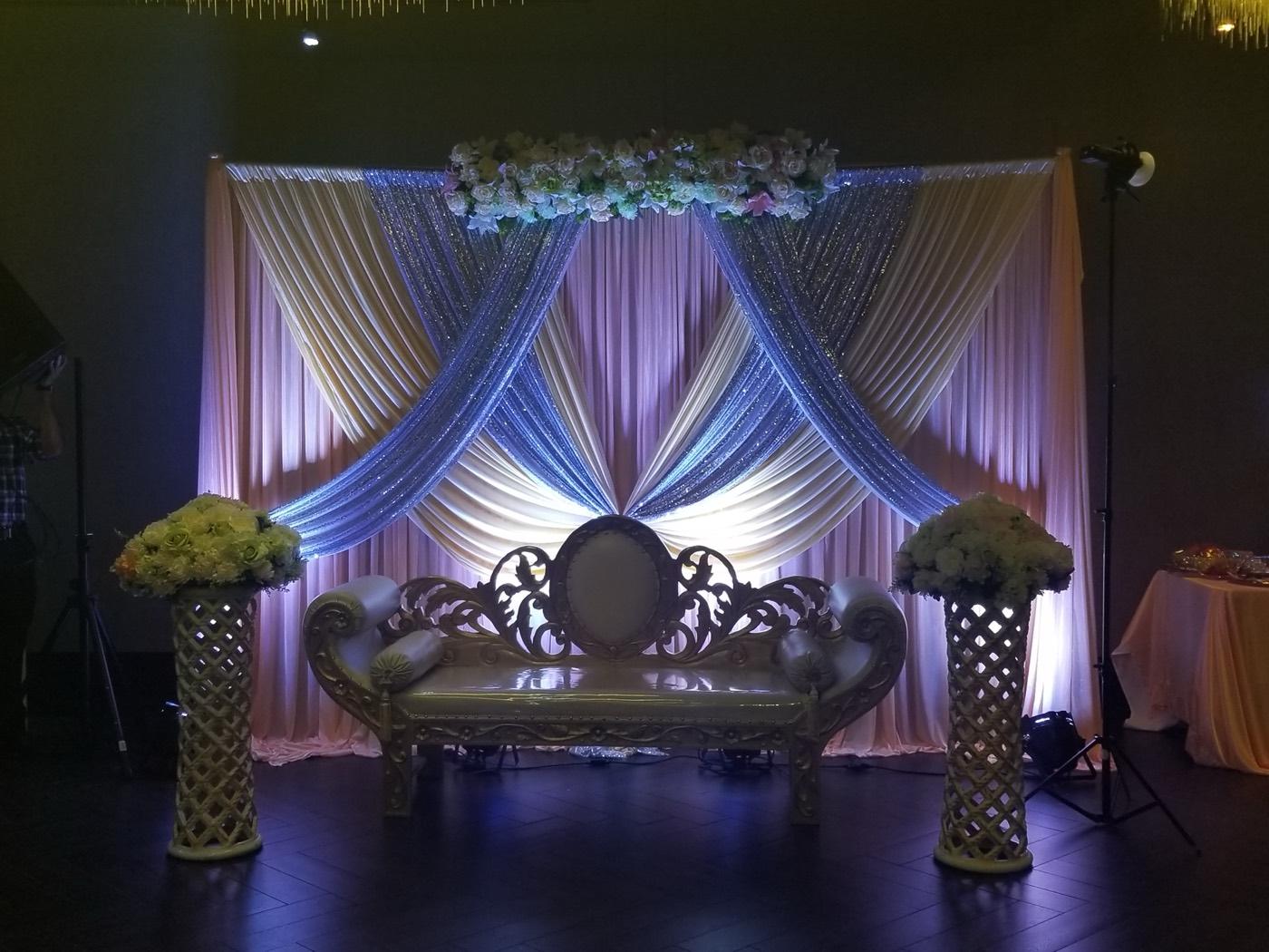 Ivory and silver draped wedding stage with gold sofa at India 101 banquet hall in Irving, TX