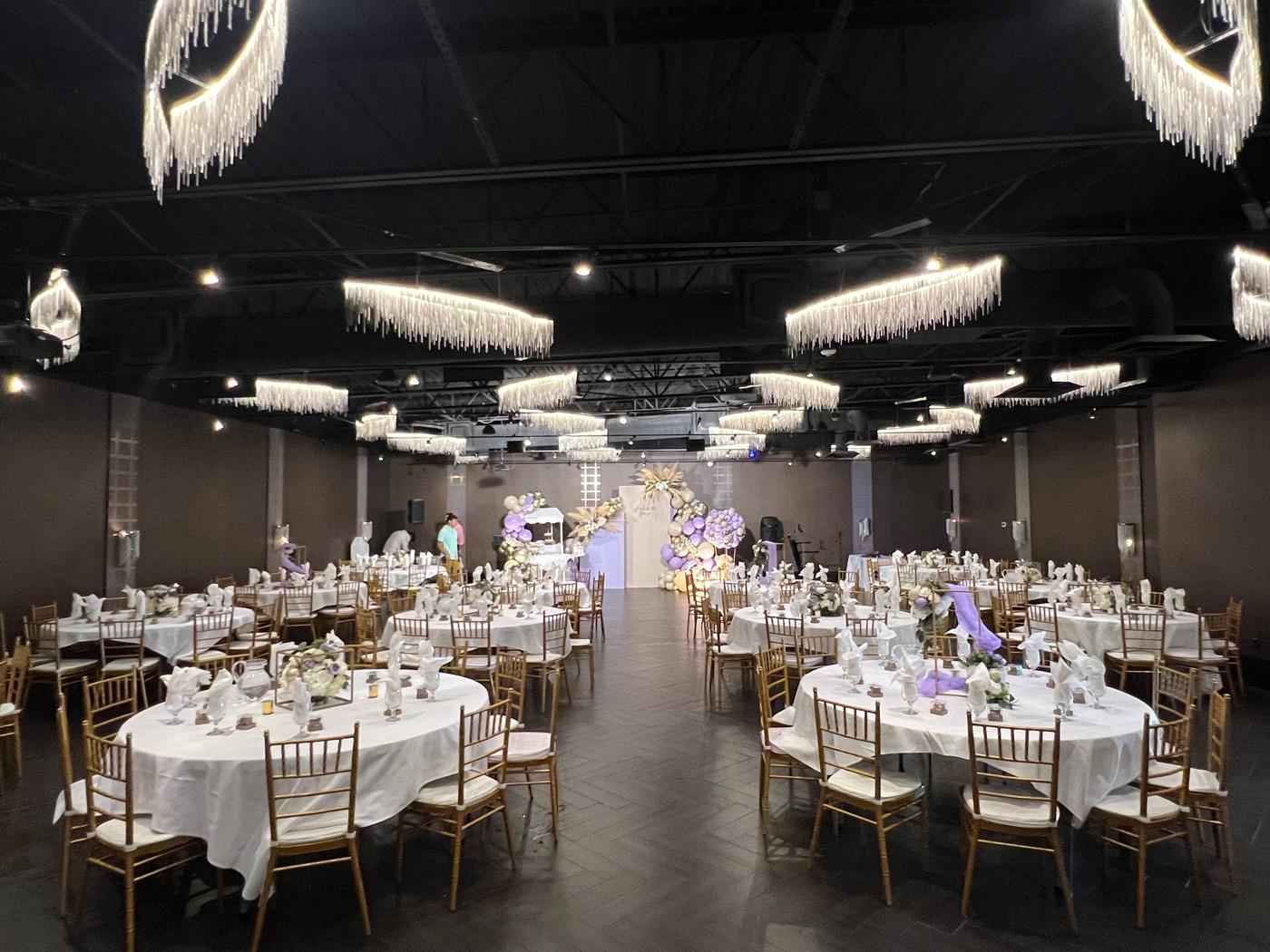 Large ballroom with lavender balloon arch and fully set tables at India 101 banquet hall in Irving, TX