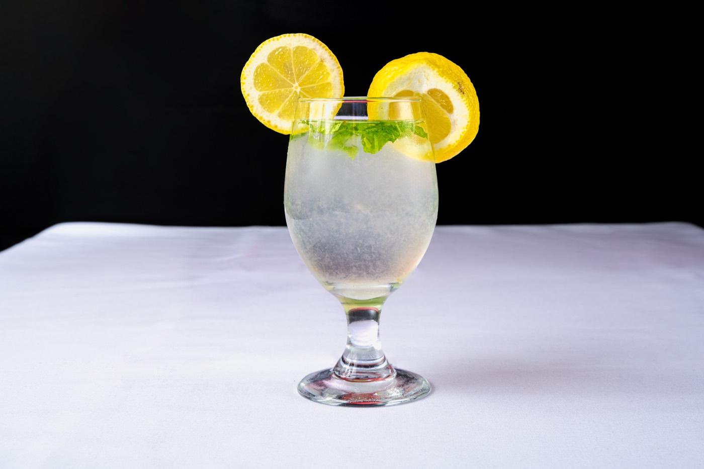 Glass of lemon mint cooler garnished with lemon slices and mint at India 101 in Irving, TX