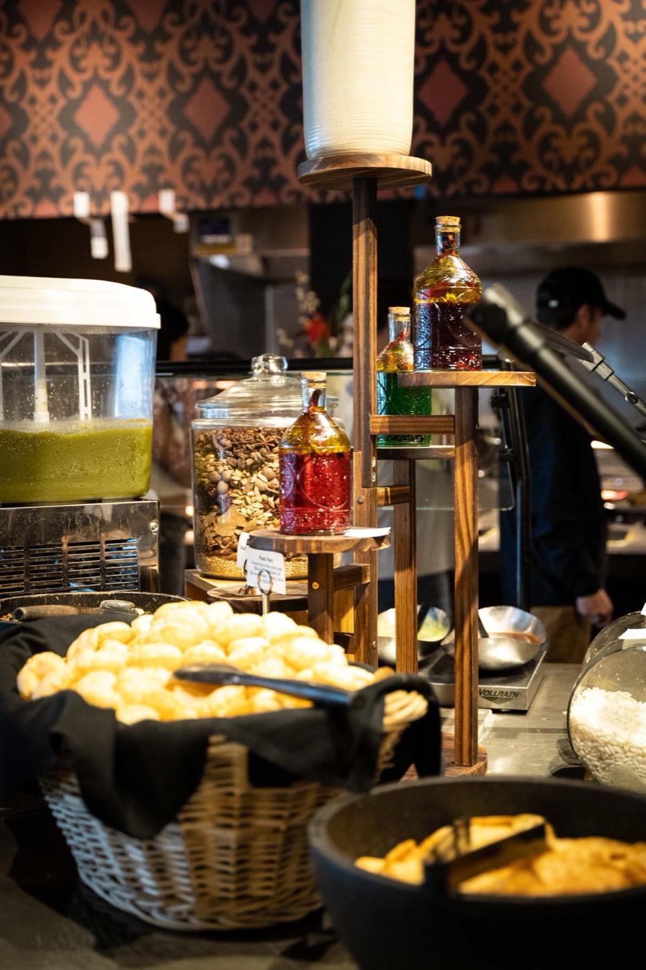 Live chaat station with crispy puri, spiced water and chutney bottles at India 101 in Irving, TX