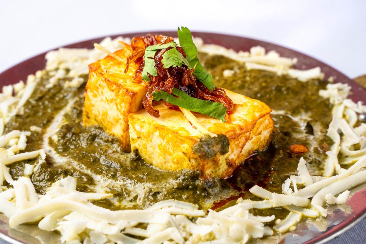 Vegetarian palak paneer with paneer cubes in spinach gravy ringed with grated cheese at India 101 in Irving, TX