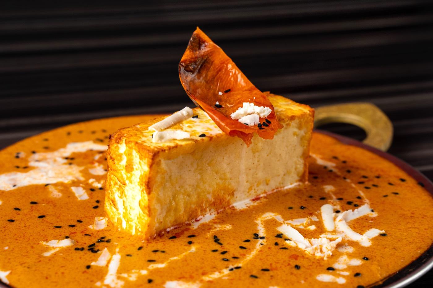 Close-up of grilled paneer block in creamy tomato gravy at India 101 in Irving, TX