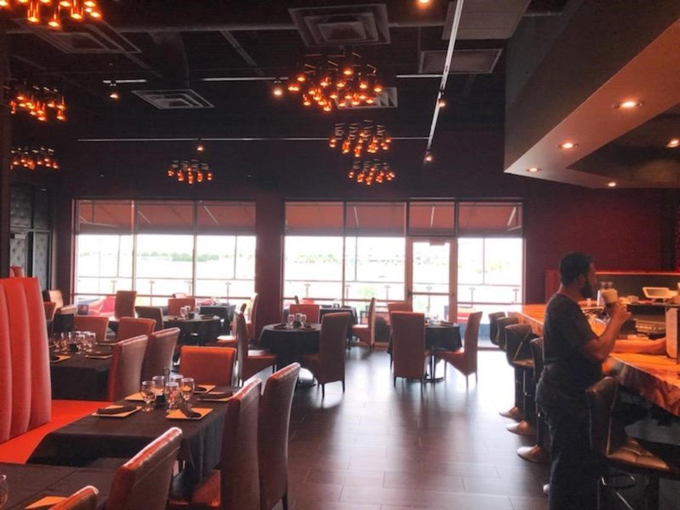 Restaurant dining room with red and tan chairs and floor-to-ceiling windows at India 101 in Irving, TX