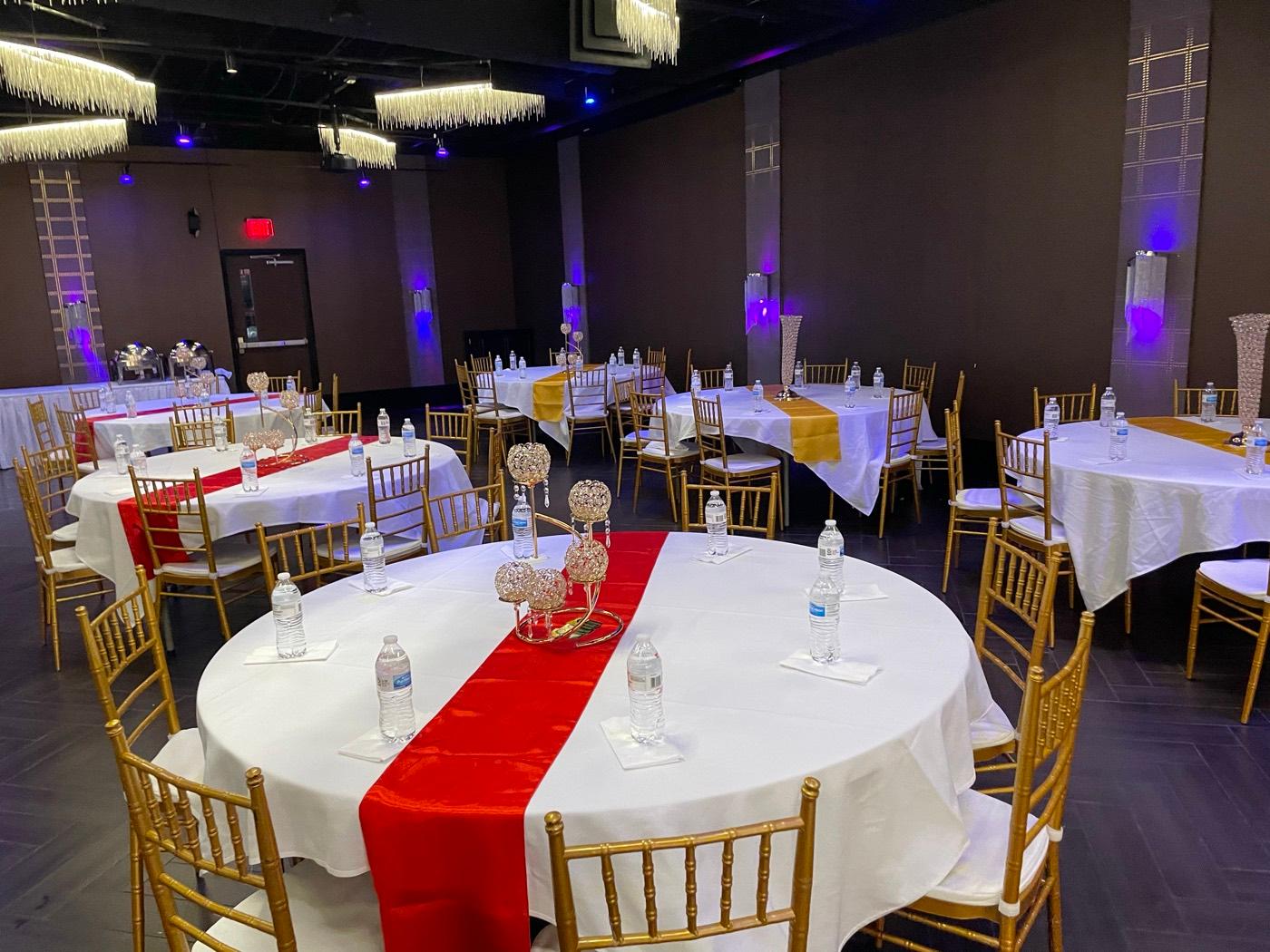Round banquet tables with red and gold runners and crystal centerpieces at India 101 in Irving, TX