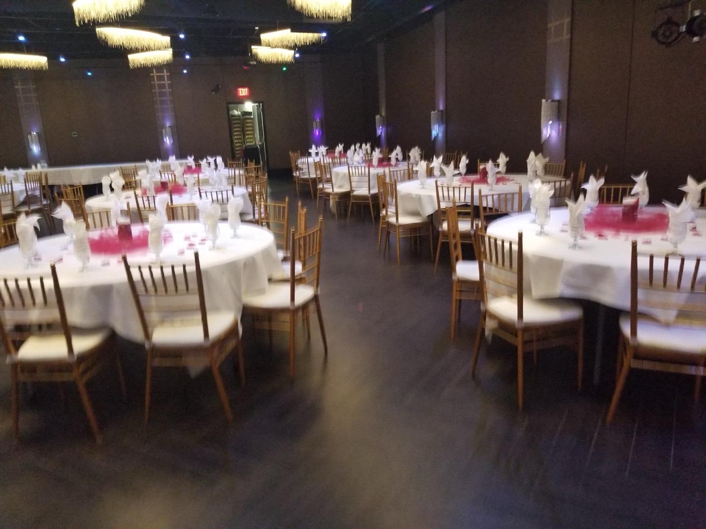 Round banquet tables in white linens with magenta accents at India 101 banquet hall in Irving, TX