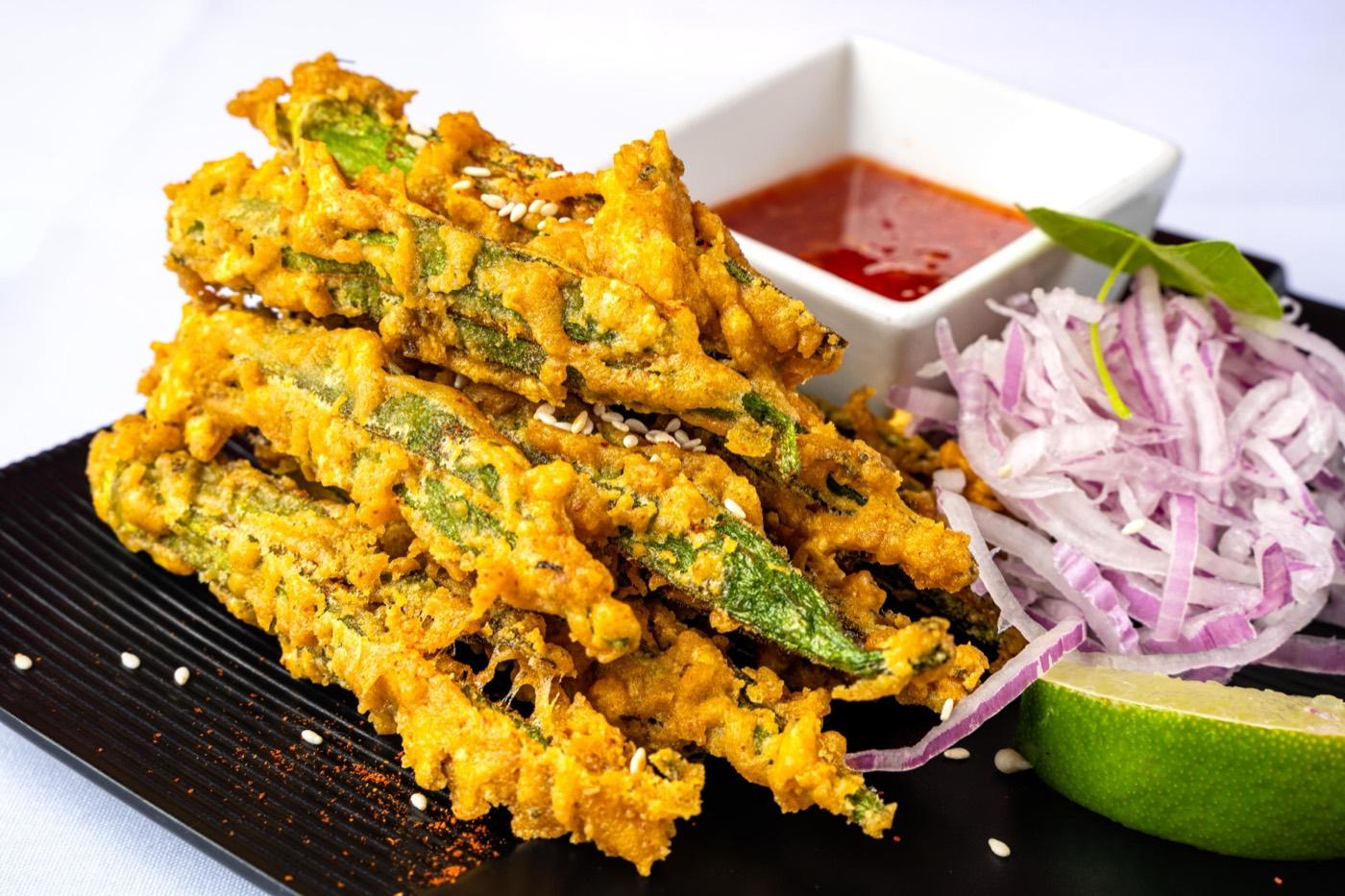 Crispy fried okra kurkuri bhindi appetizer with sliced onions and lime