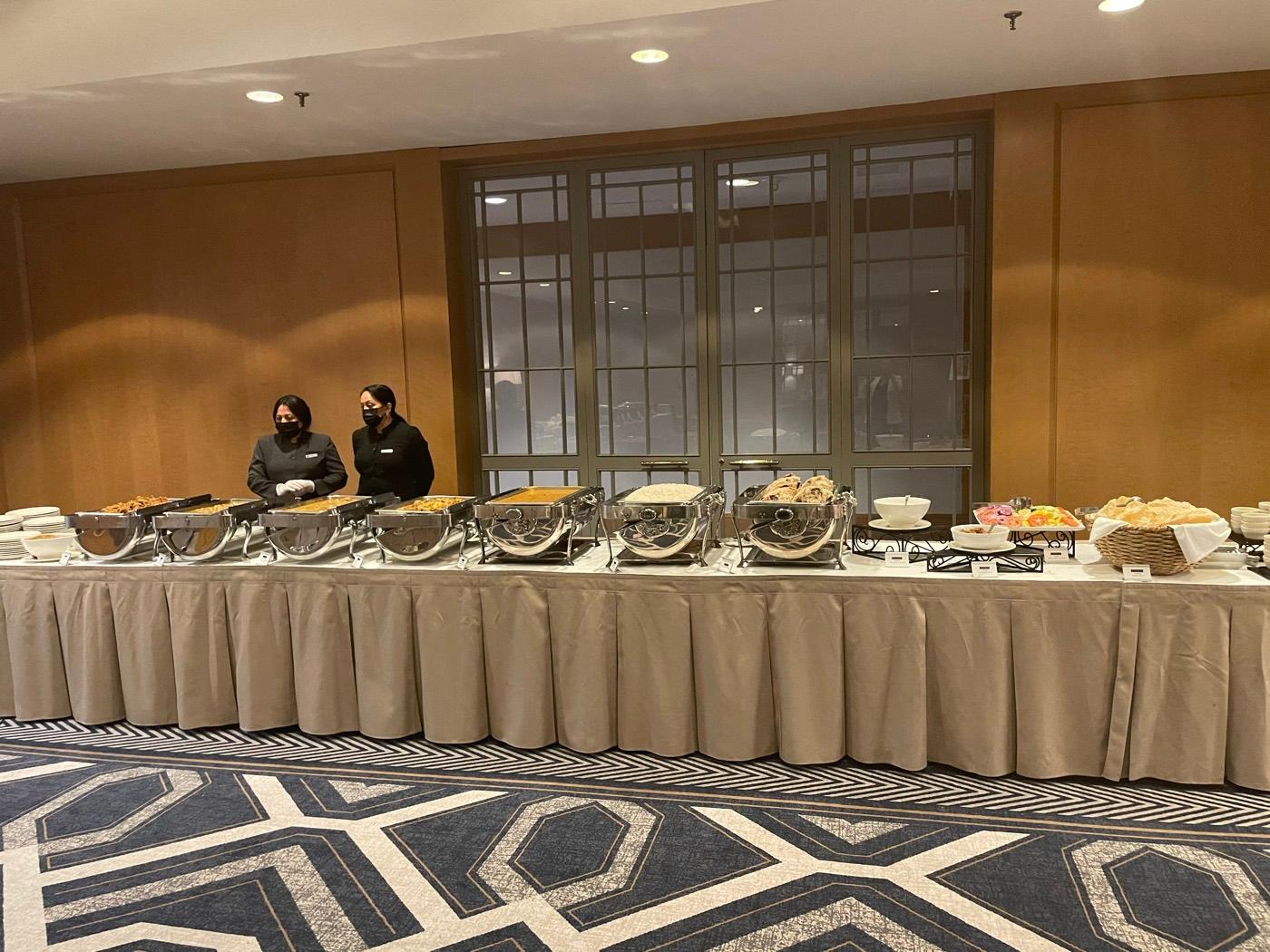 Uniformed catering staff standing by a chafing-dish buffet table set by India 101 in Irving, TX