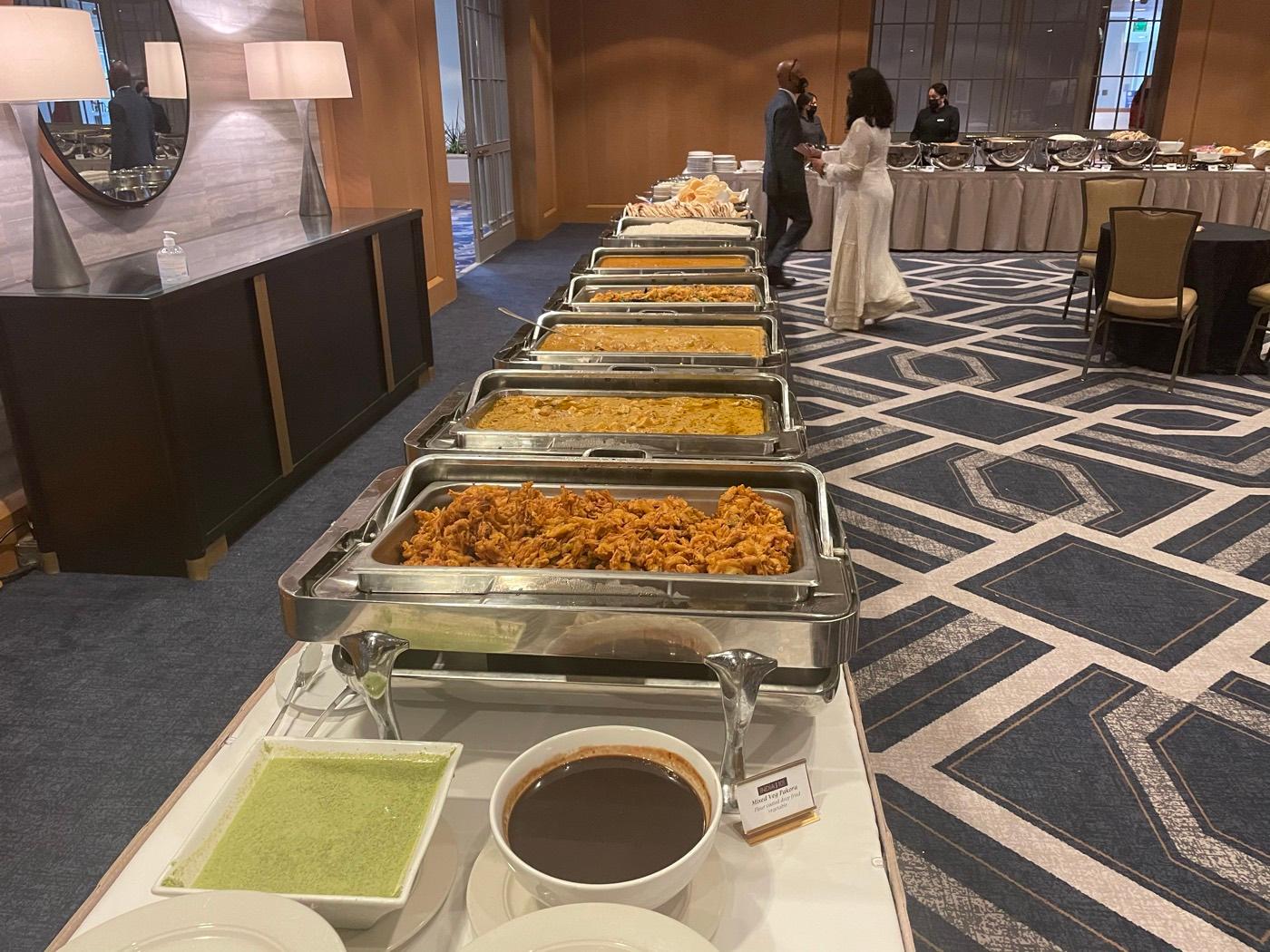 Long chafing-dish catering line with fritters, curries, and chutneys served by India 101 in Irving, TX