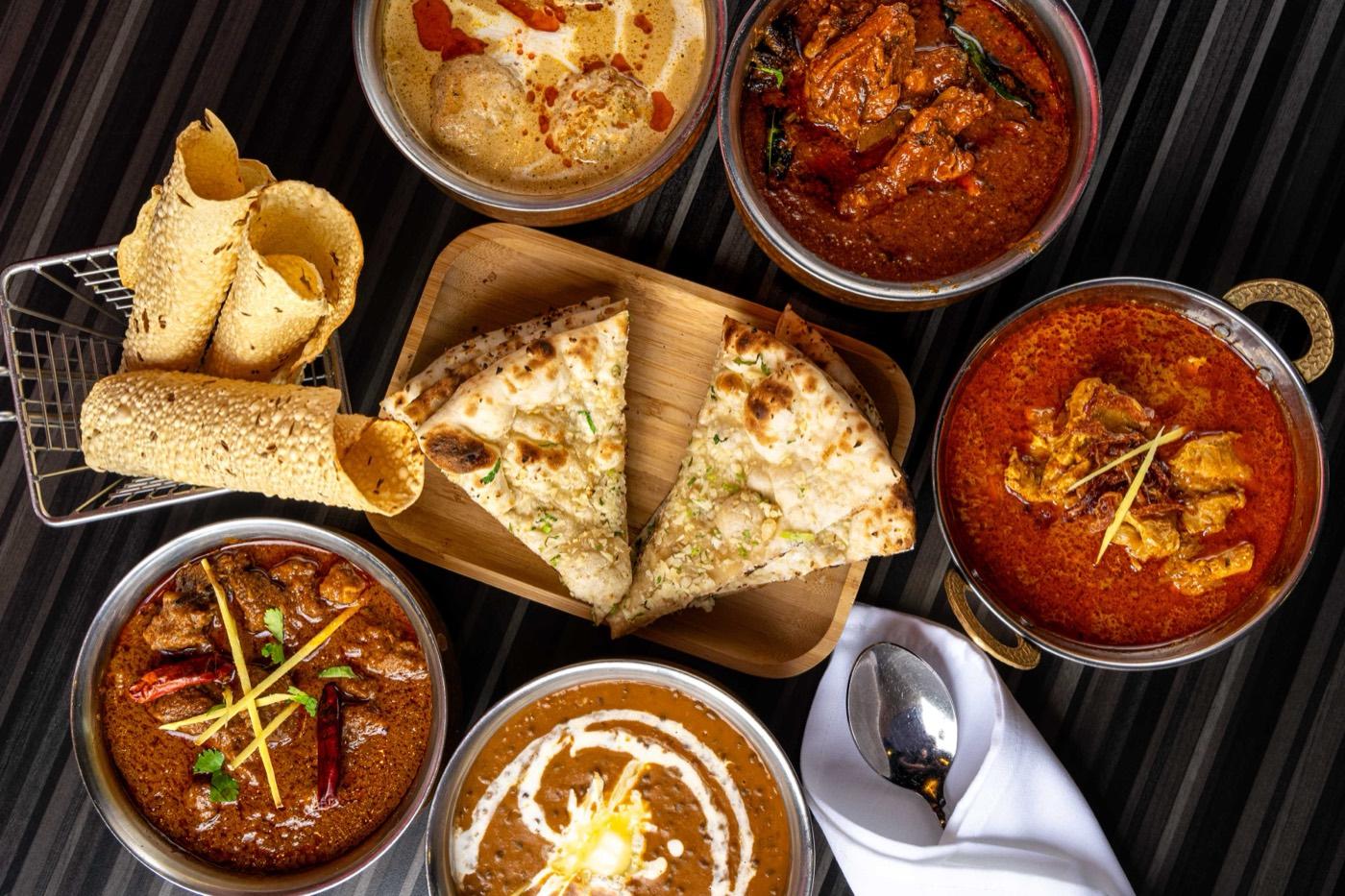 Overhead spread of North Indian curries, dal makhani and garlic naan at India 101